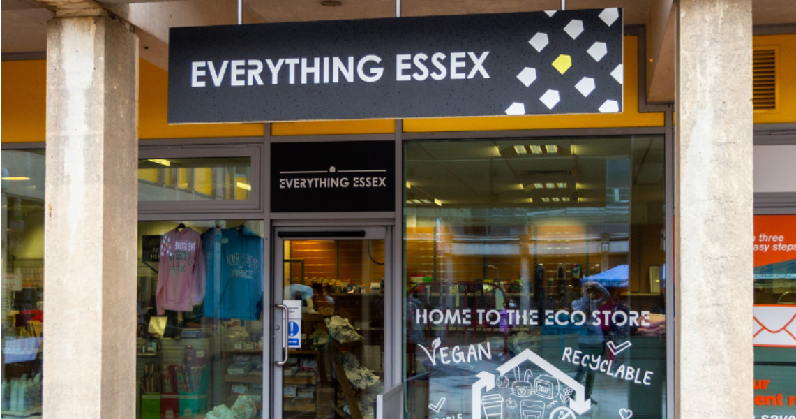 Exterior of the University of Essex Student Union shop, the sign reads "Everything Essex" and the store has a glass front with "Home to the Eco Store", "Vegan" and "Recyclable" printed on the window